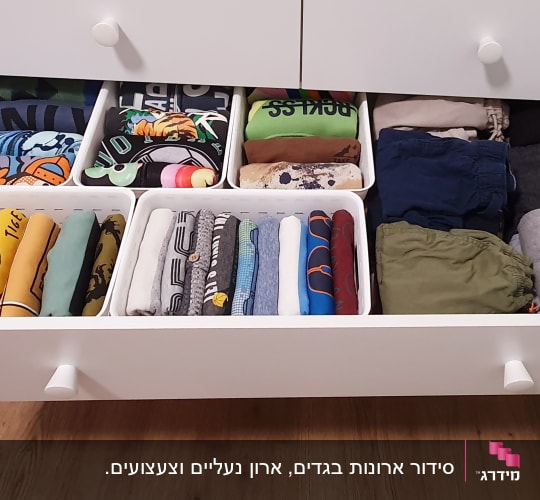מגירה פתוחה עם בגדים מקופלים ומאורגנים בסלים